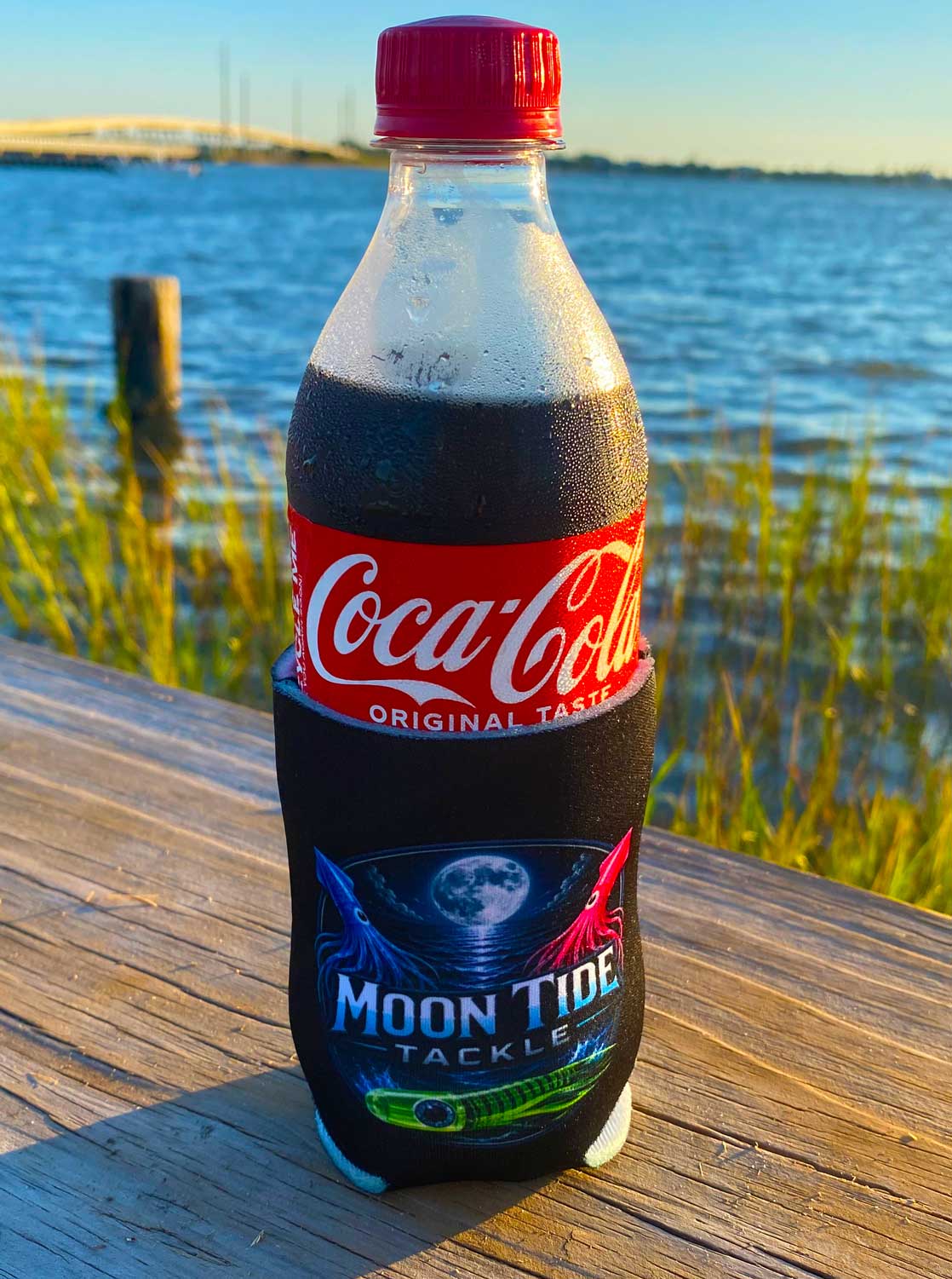 Moon Tide Tackle black koozie holding a beverage beside the water
